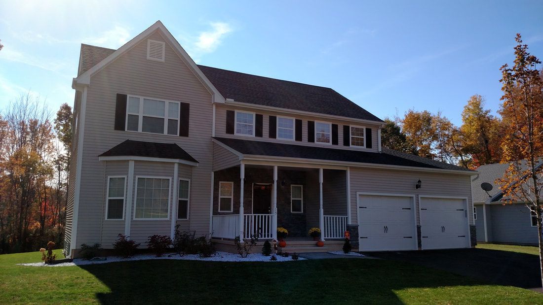 A large house with a porch and two garages