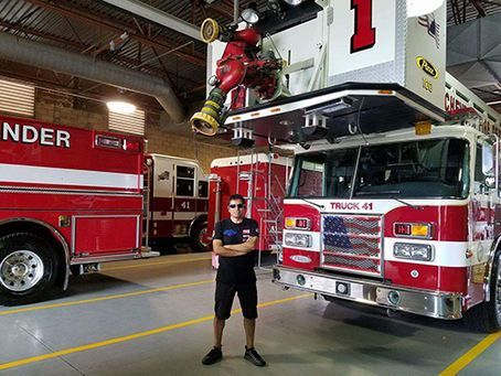 A man is standing in front of a fire truck in a garage.