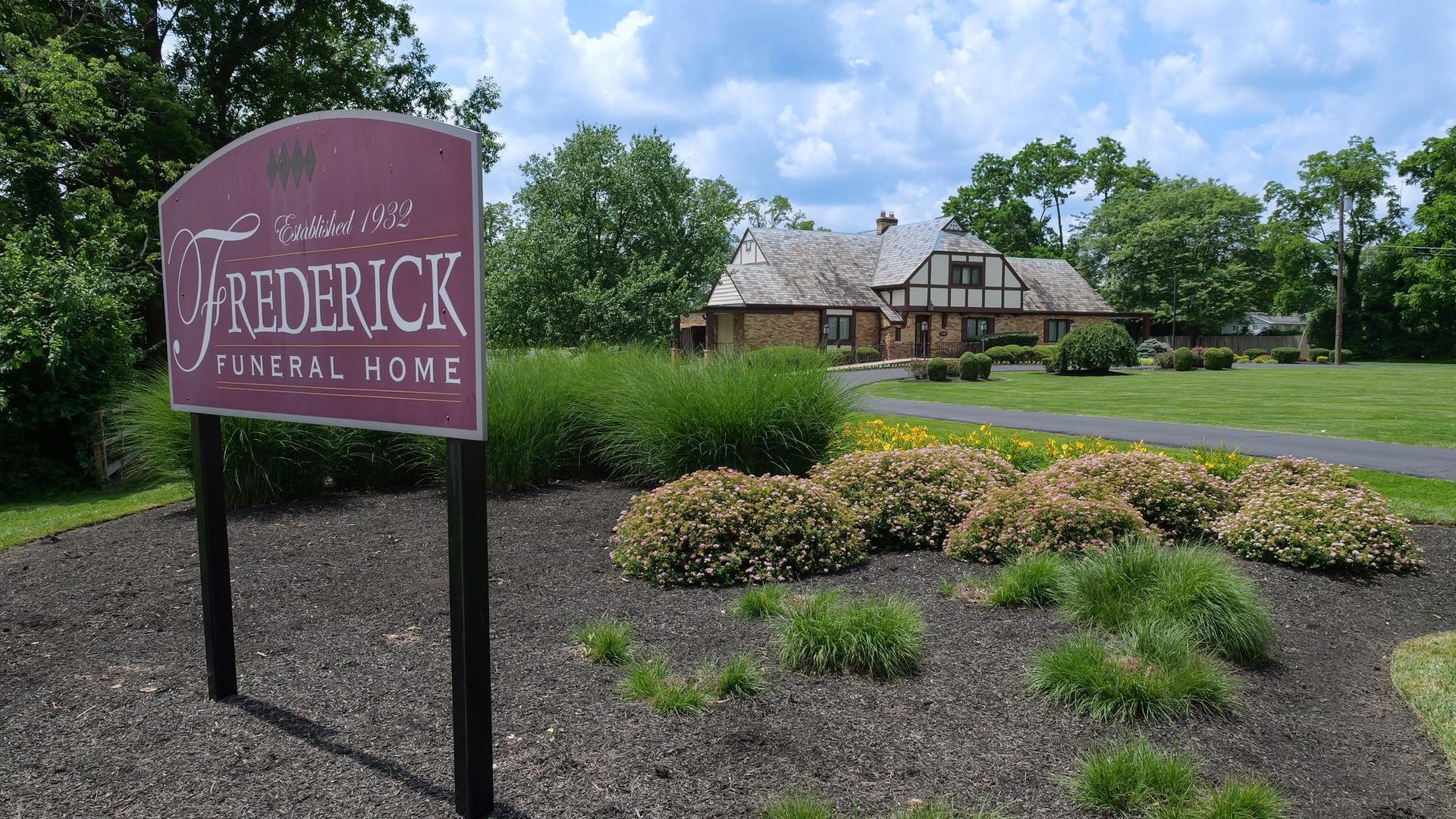 Frederick Motor Inn sign in front of a landscaped lawn and lodge-style building under a blue sky
