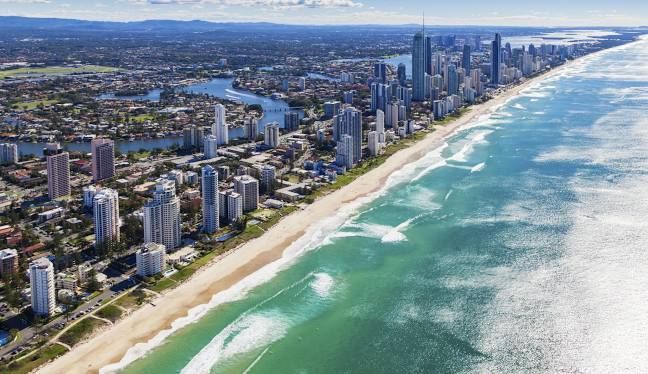 Coastal city skyline next to a beach with turquoise water on a sunny day.