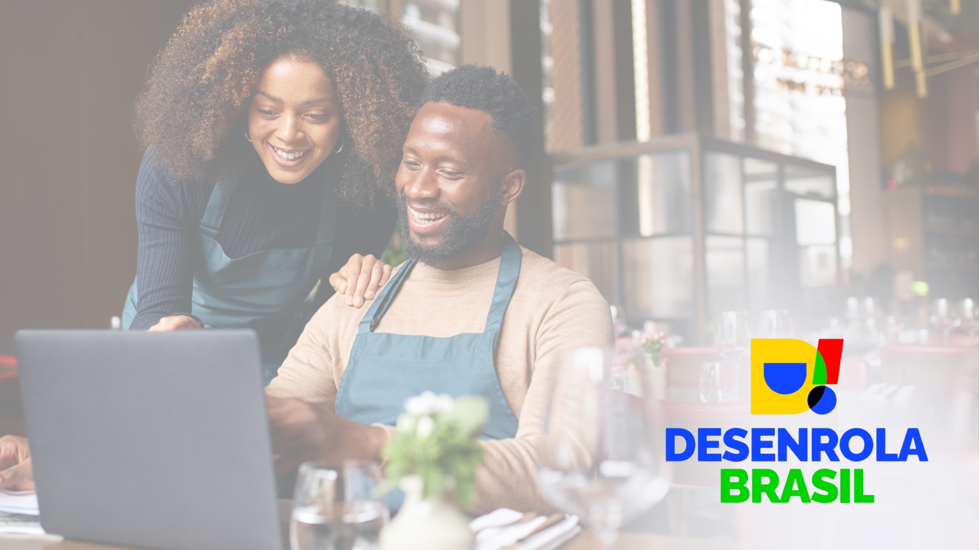 Um homem e uma mulher estão olhando para um laptop em um restaurante.