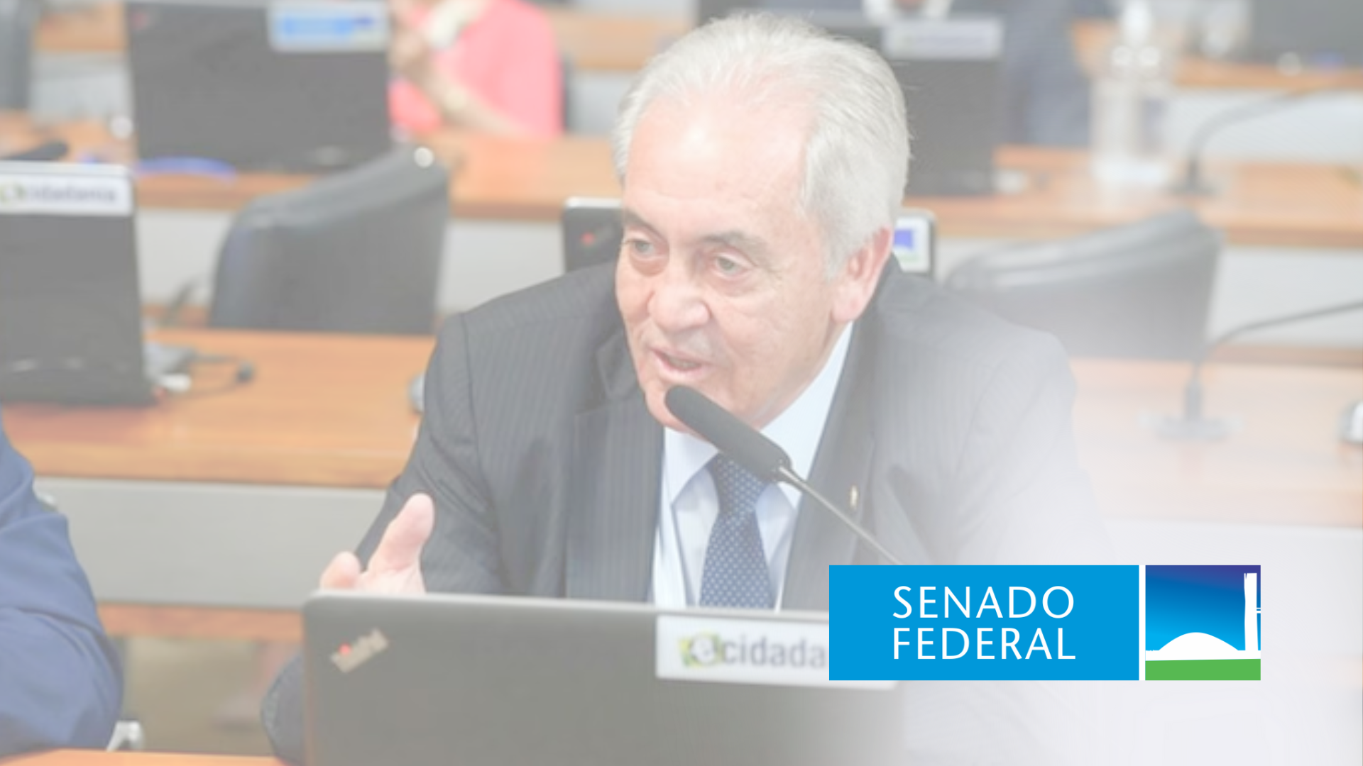Um homem de terno e gravata está sentado em frente a um laptop.