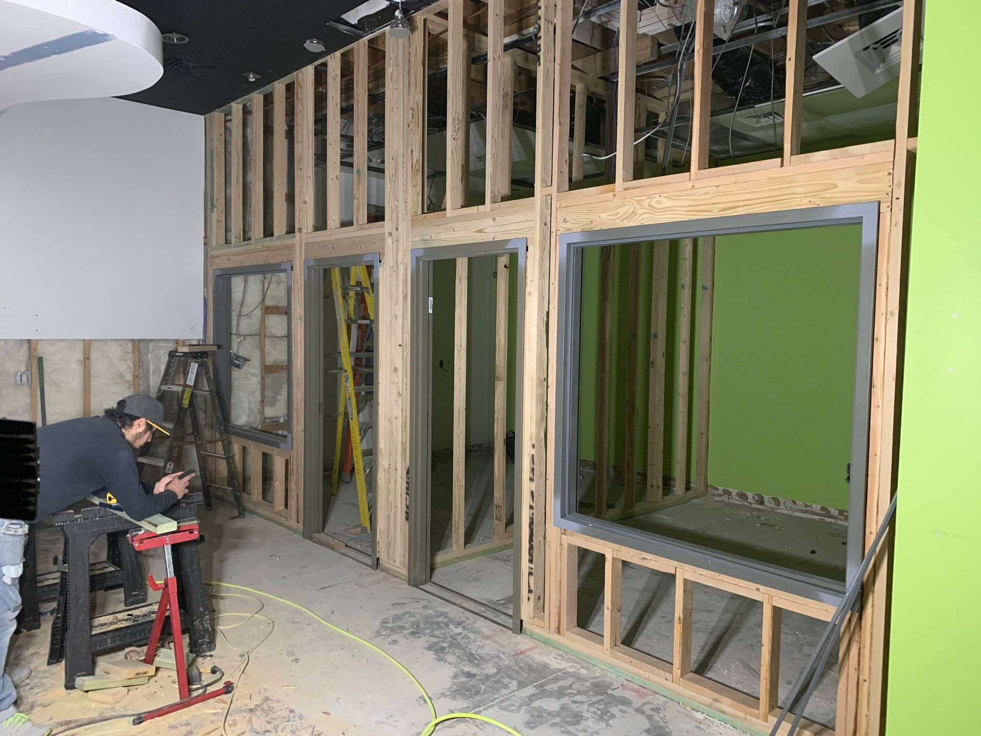 Construction workers framing a wall with large windows in an unfinished interior space