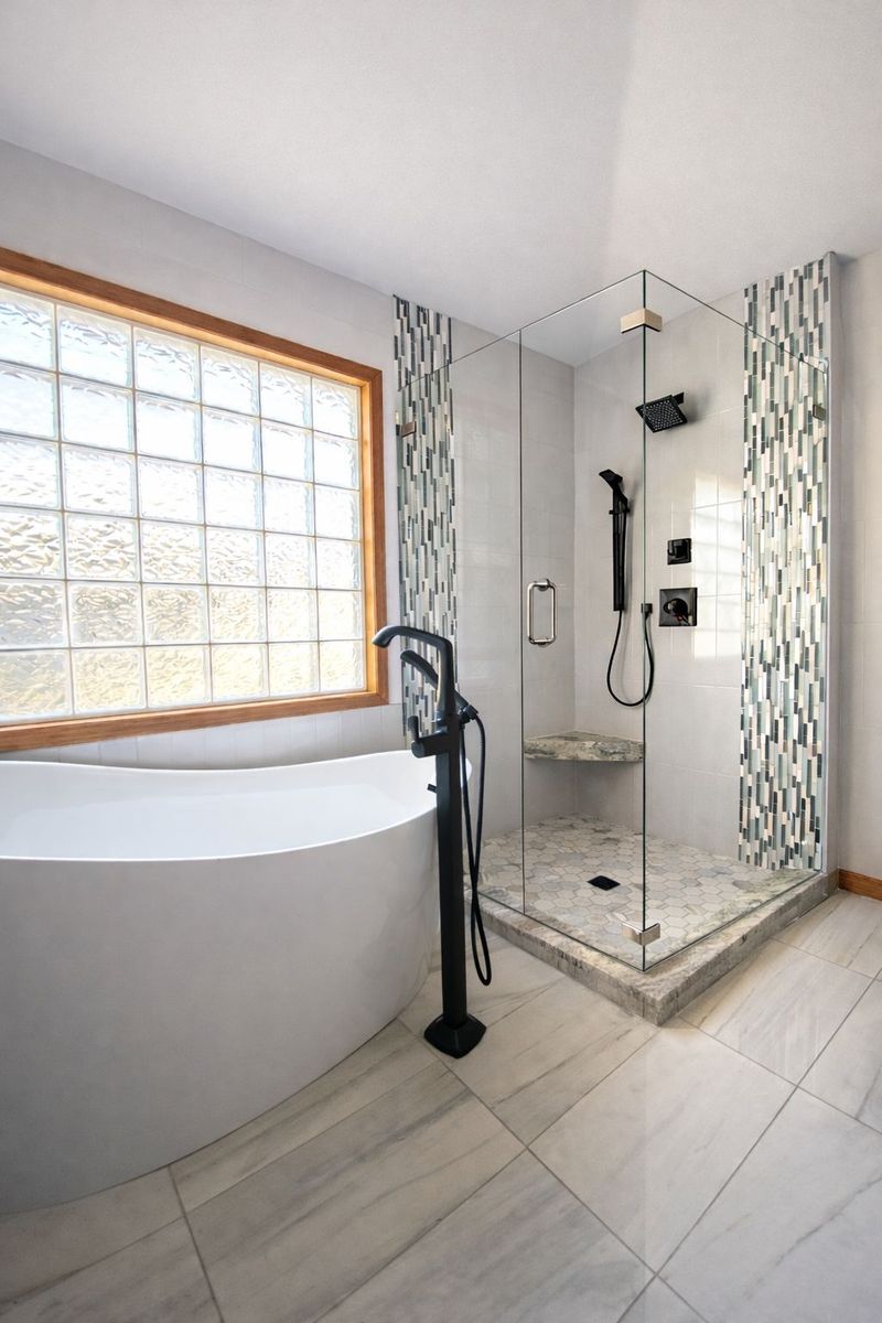 Bathroom with freestanding tub, glass-block window, and tiled walk-in shower with handheld showerhead