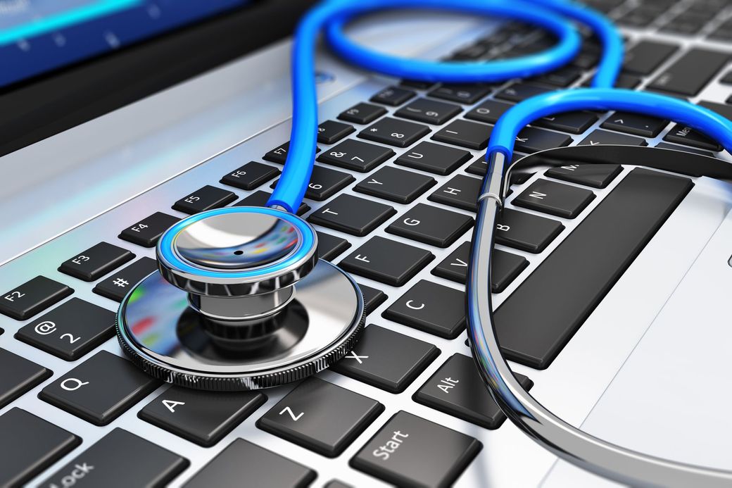Uno stetoscopio blu appoggiato sulla tastiera nera di un computer portatile.