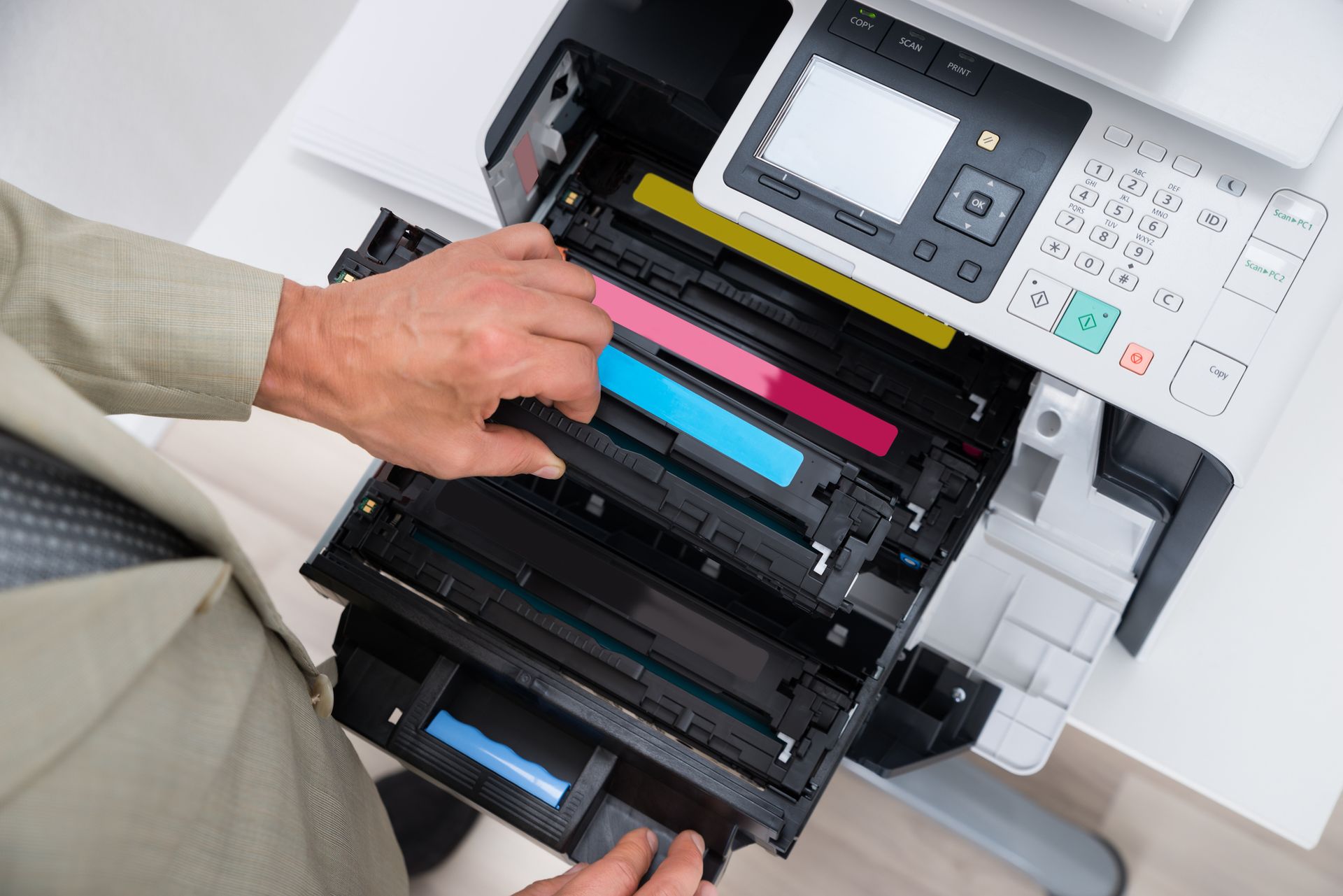 Persona che sostituisce le cartucce del toner in una stampante a colori; mani che inseriscono le cartucce.