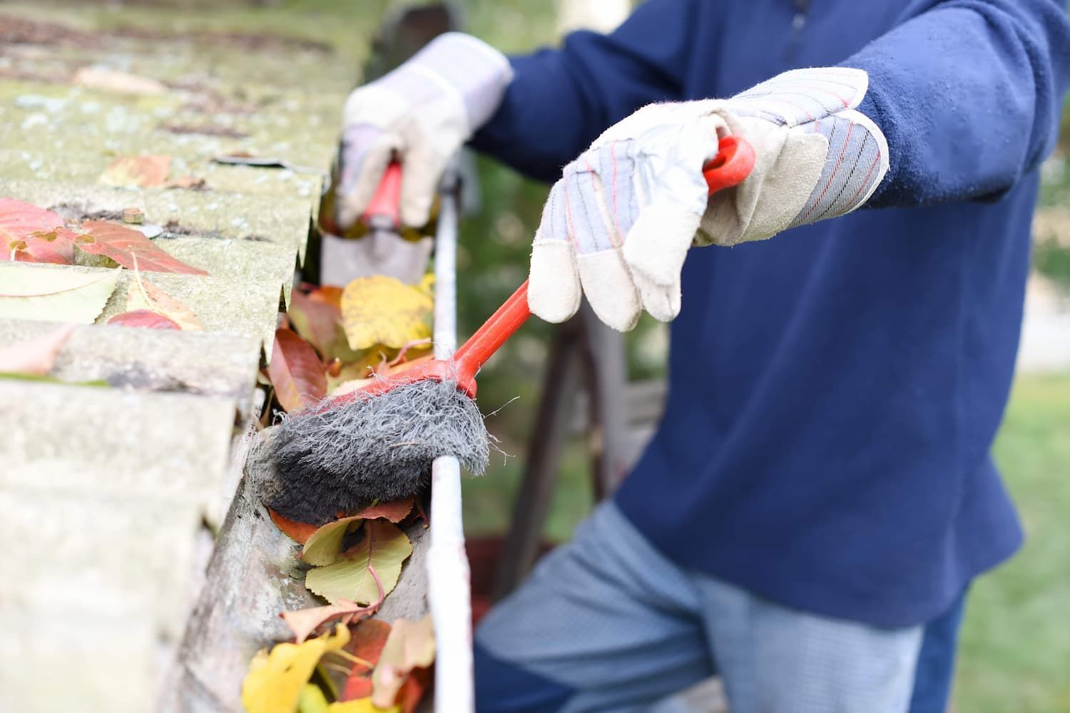 A Person is Cleaning a Gutter With a Brush — John Day Plumbing in Howard Springs, NT