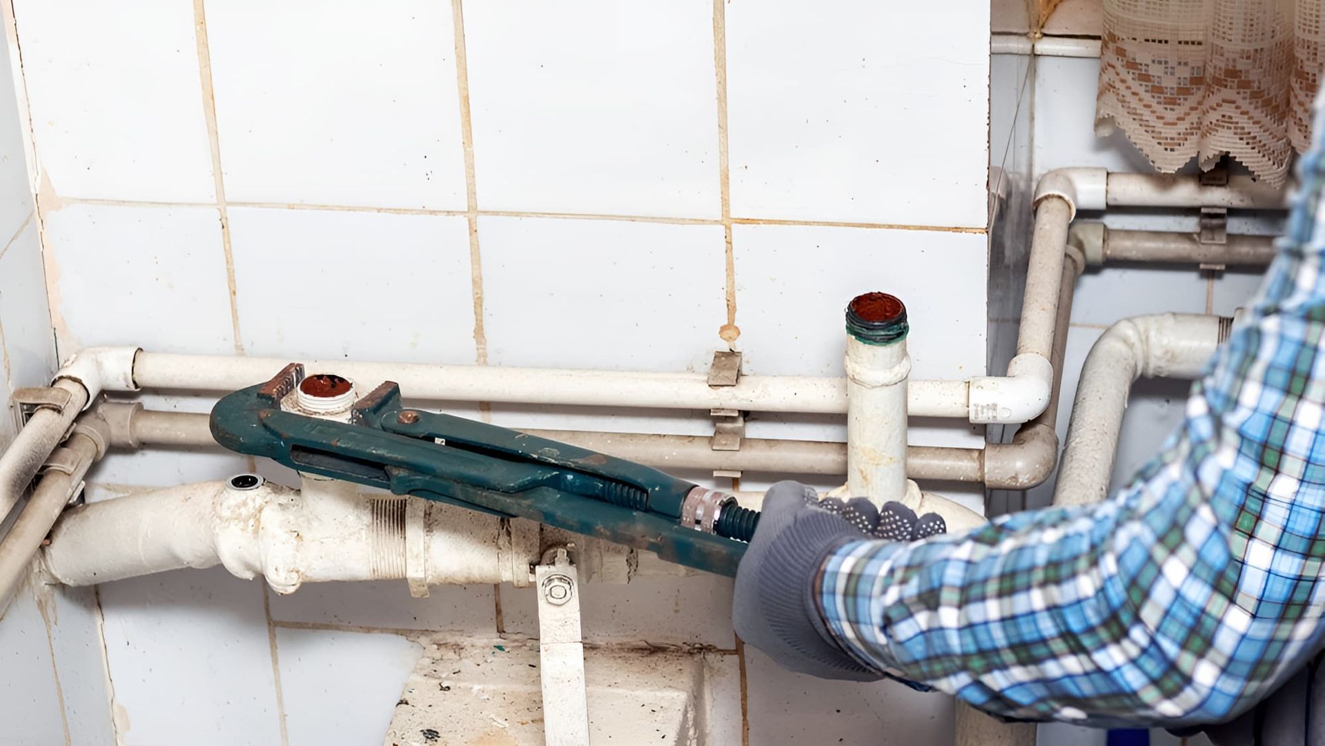 A Man is Fixing a Pipe With a Wrench in a Bathroom — John Day Plumbing in Palmerston, NT