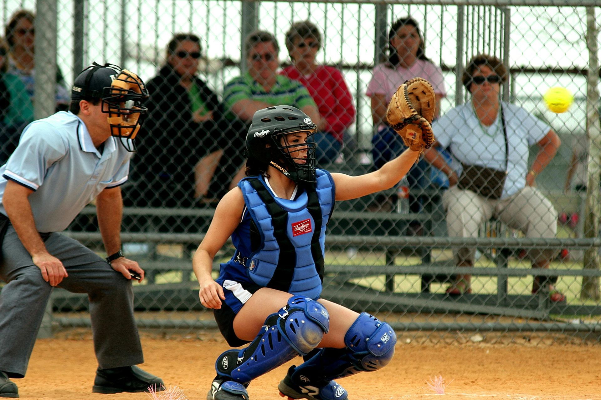 Baseball player sliding into home plate, catcher in front. Blue and gold uniforms, action shot.
