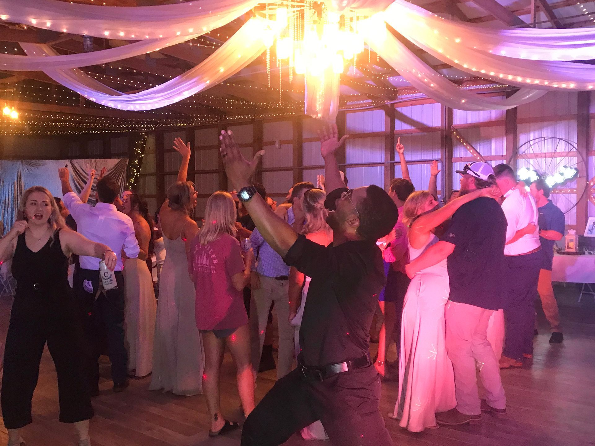 People dancing at a decorated indoor event with purple drapes and bright lights