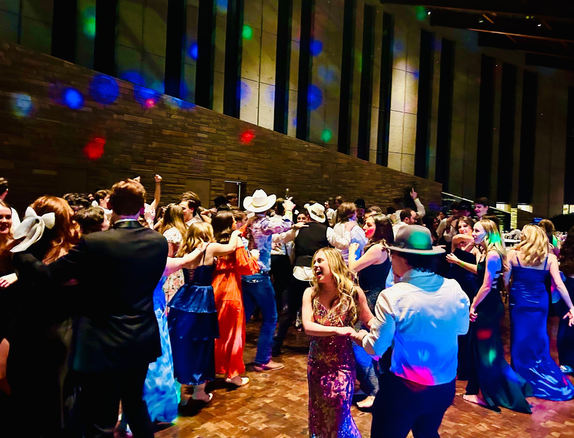 People dancing at a lively indoor party with colorful lights and formal attire.