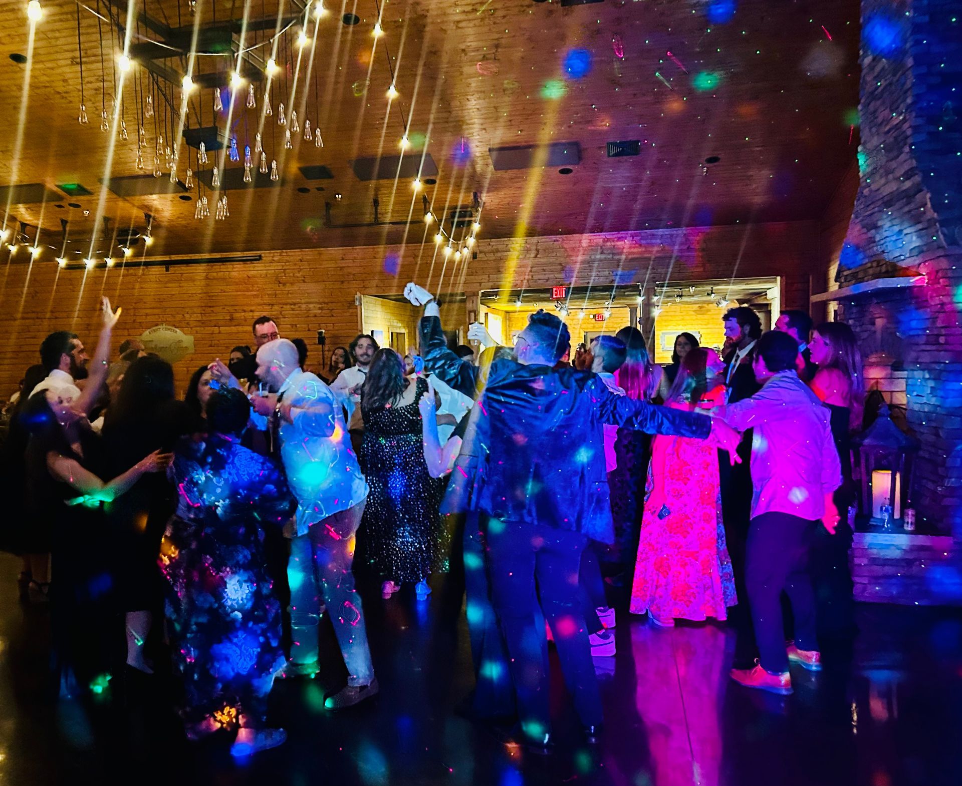 People dancing at a colorful indoor party with disco lights and a sparkly floor