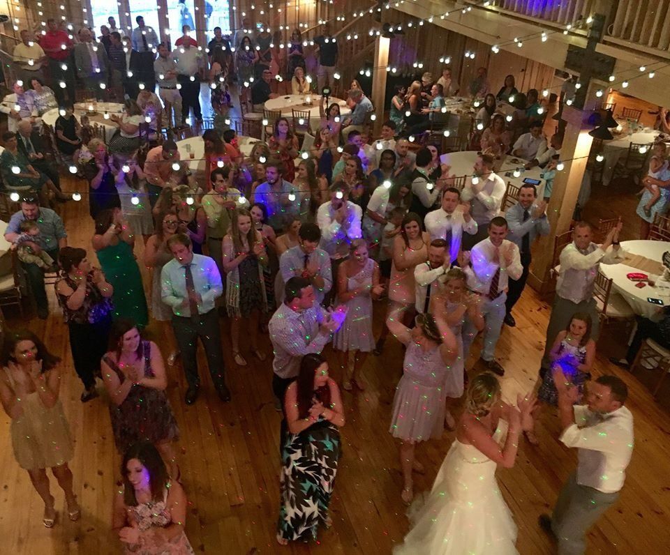 Guests dancing and mingling in a warmly lit ballroom at a lively party with colored lights