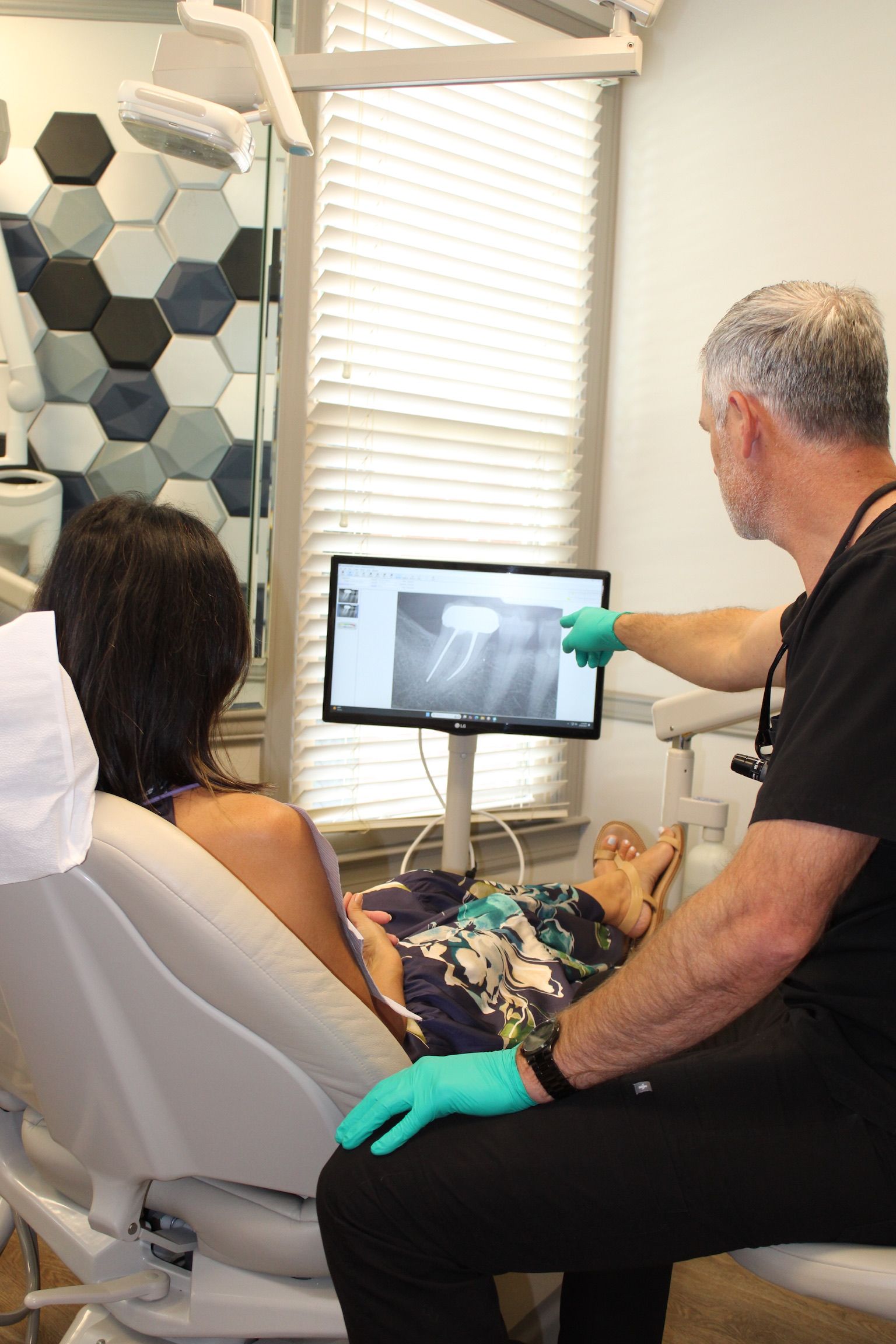 A dental assistant and dentist attending to a patient in a modern dental office.