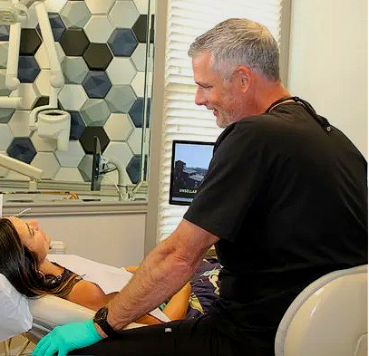 A dental assistant and dentist attending to a patient in a modern dental office.