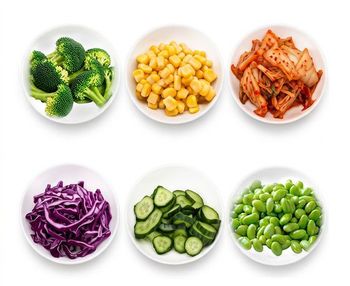 Six white bowls of vegetables: broccoli, corn, kimchi, red cabbage, cucumber slices, and edamame.