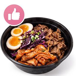 Black bowl of assorted Korean-style food with eggs, meat, and spicy cabbage, plus a pink thumbs-up icon
