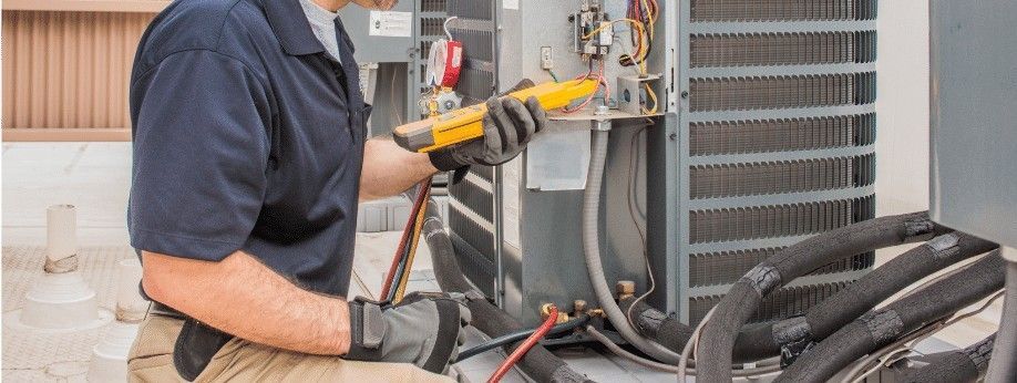 HVAC technician working on an air conditioner unit with a yellow testing tool.