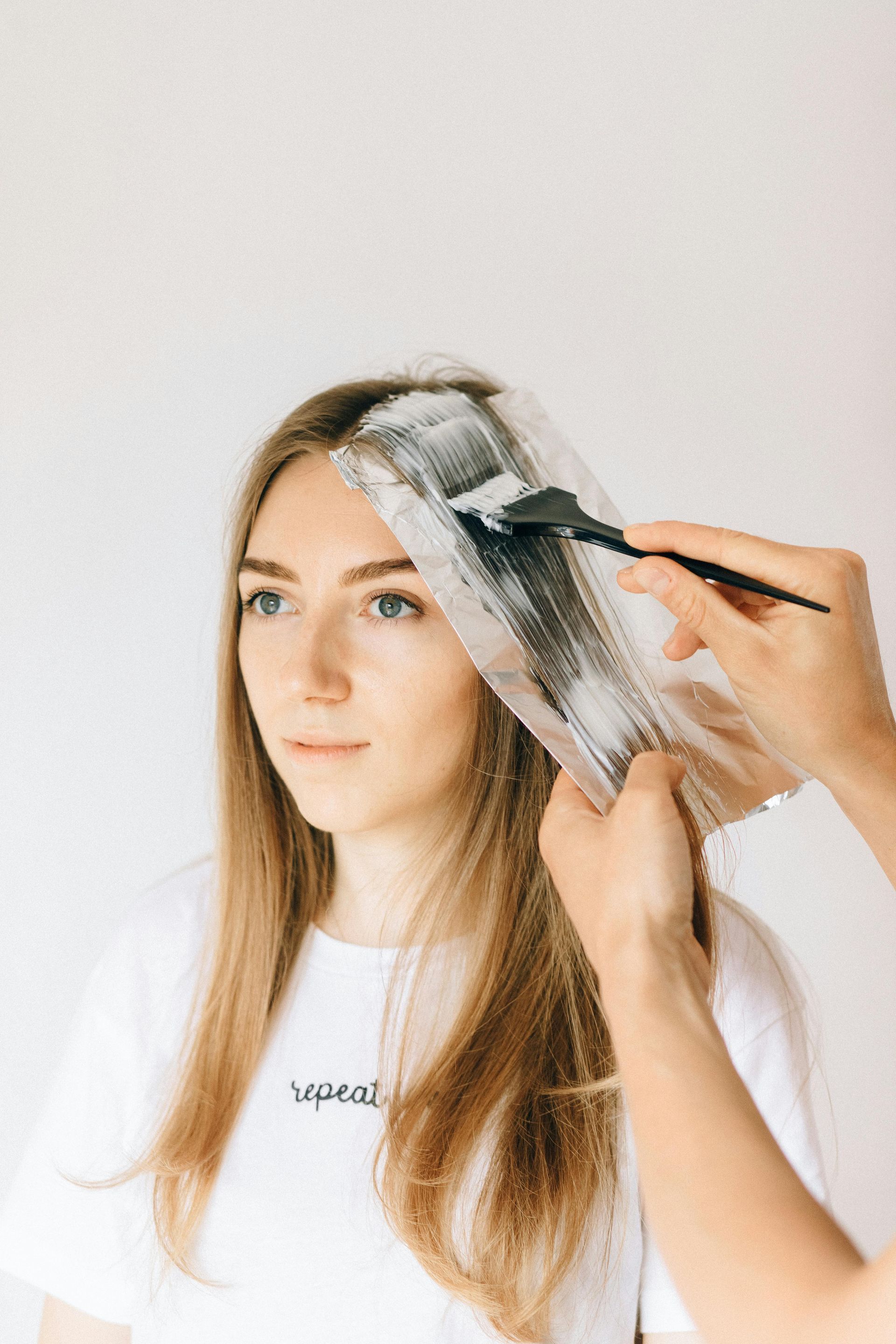 Mujer con cabello largo y rubio recibiendo reflejos en un salón.