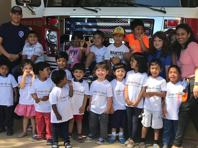 Group of children and adults posing in front of a food truck, many wearing white shirts and smiling