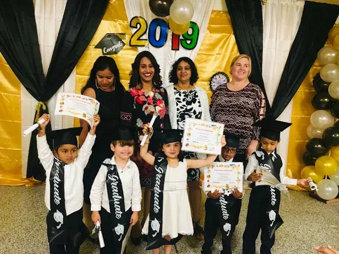 Group posing on stage with 2019 backdrop, balloons, and certificates, celebrating an event
