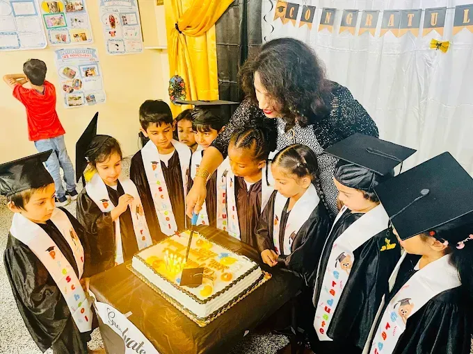 Children gathered around a cake, smiling and celebrating in a decorated classroom.