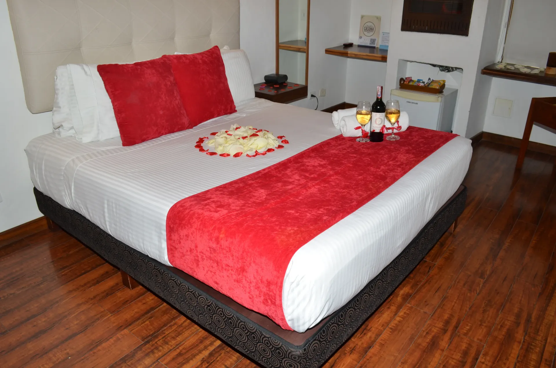 Romantic bedroom: Red accents on bed with wine and roses.