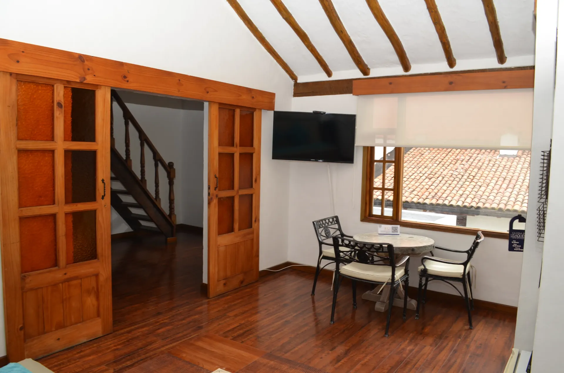 Interior of a room with hardwood floors, wooden sliding doors, and a small table set near a window.