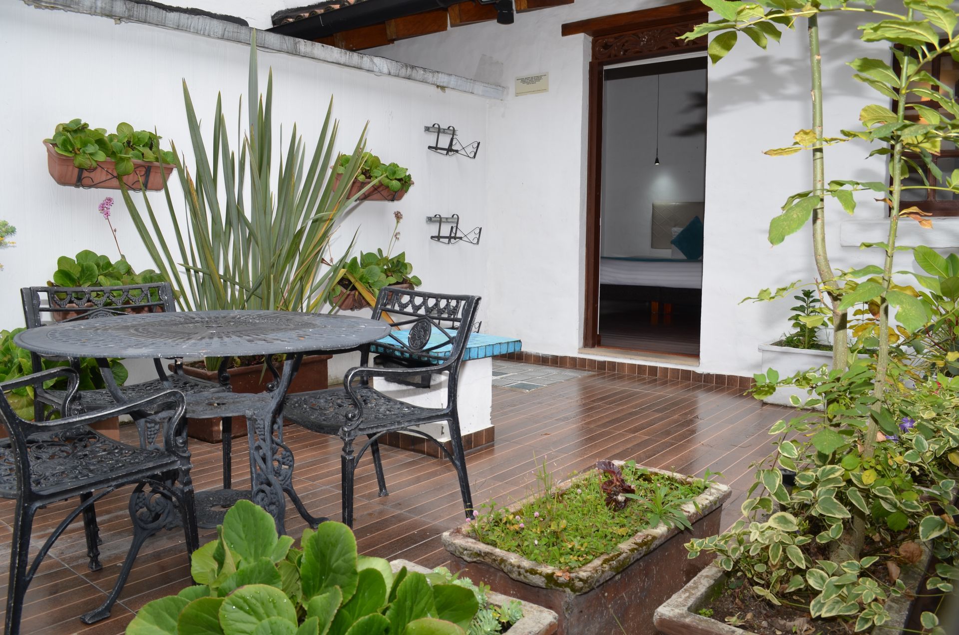 Patio with table and chairs, potted plants, and doorway leading to a bedroom.
