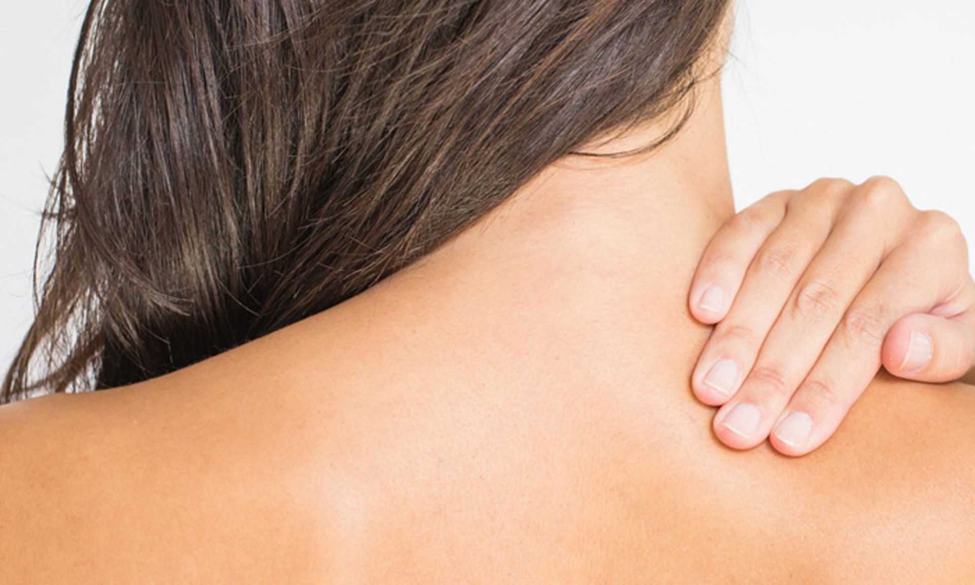 A woman is holding her neck with her hand.