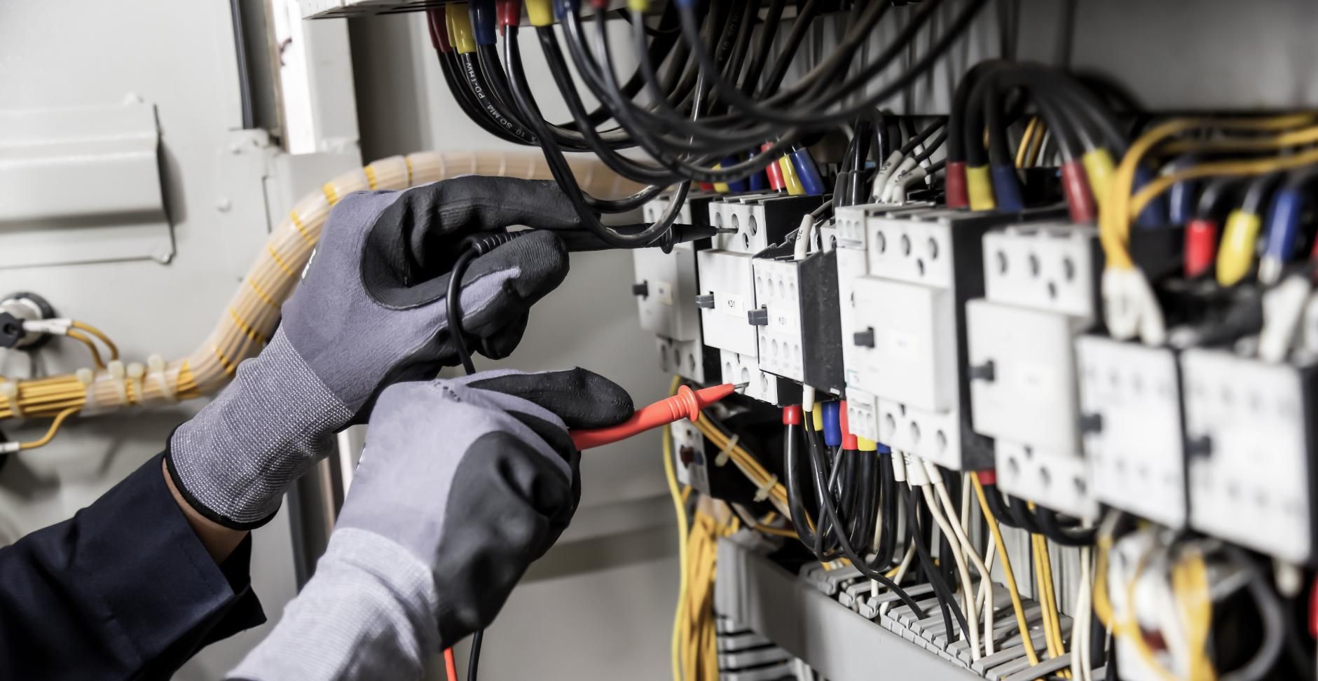 An Electrician is Working on an Electrical Panel With a Multimeter — Power & Data Support Services In Tully, QLD