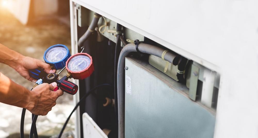 A Man is Working on an Air Conditioner With Two Gauges — Power & Data Support Services In Mareeba, QLD