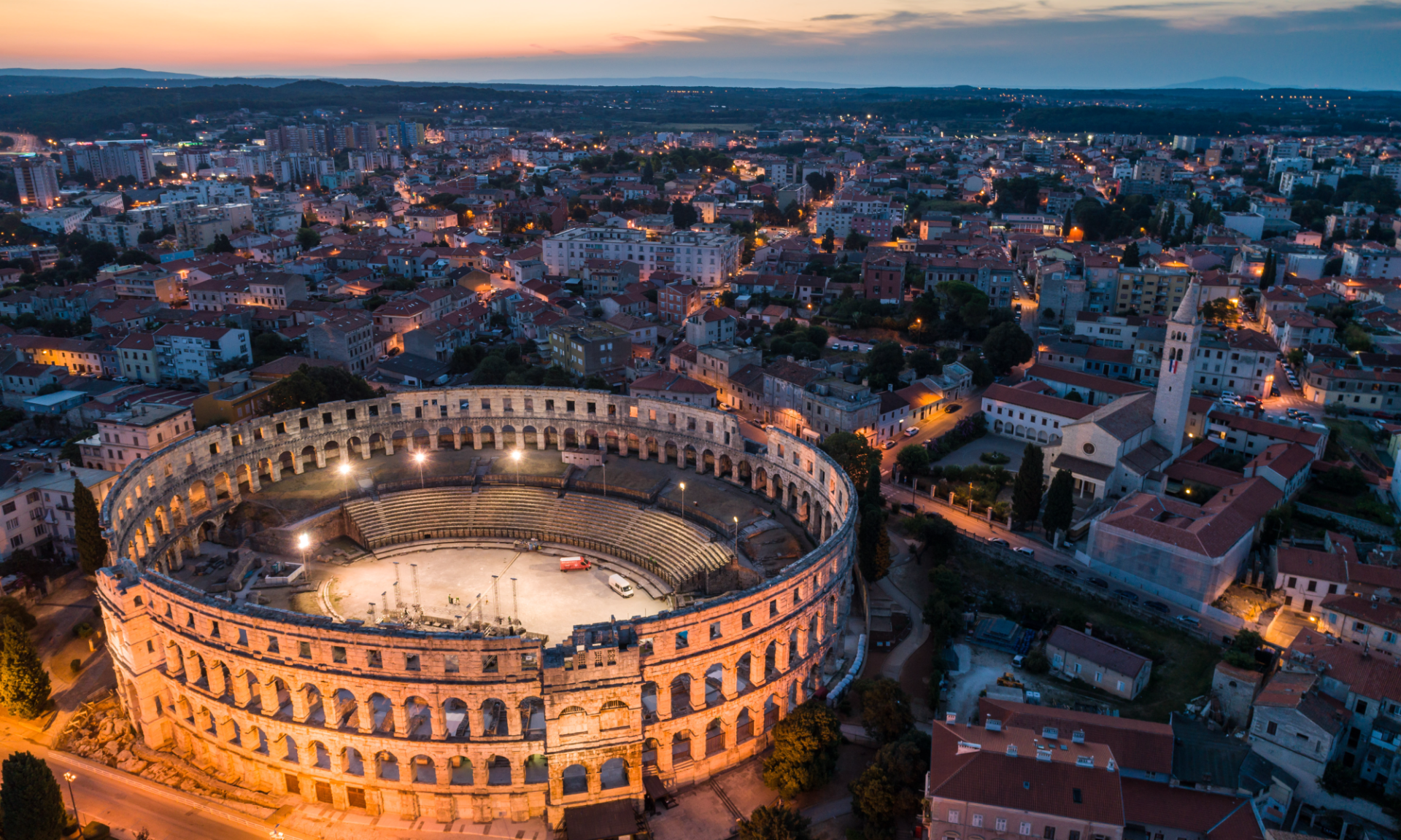An aerial view of an ancient roman amphitheater at night.