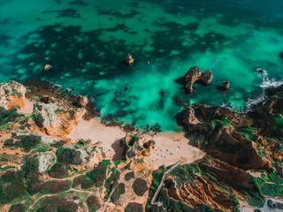 An aerial view of a beach surrounded by rocks and turquoise water.