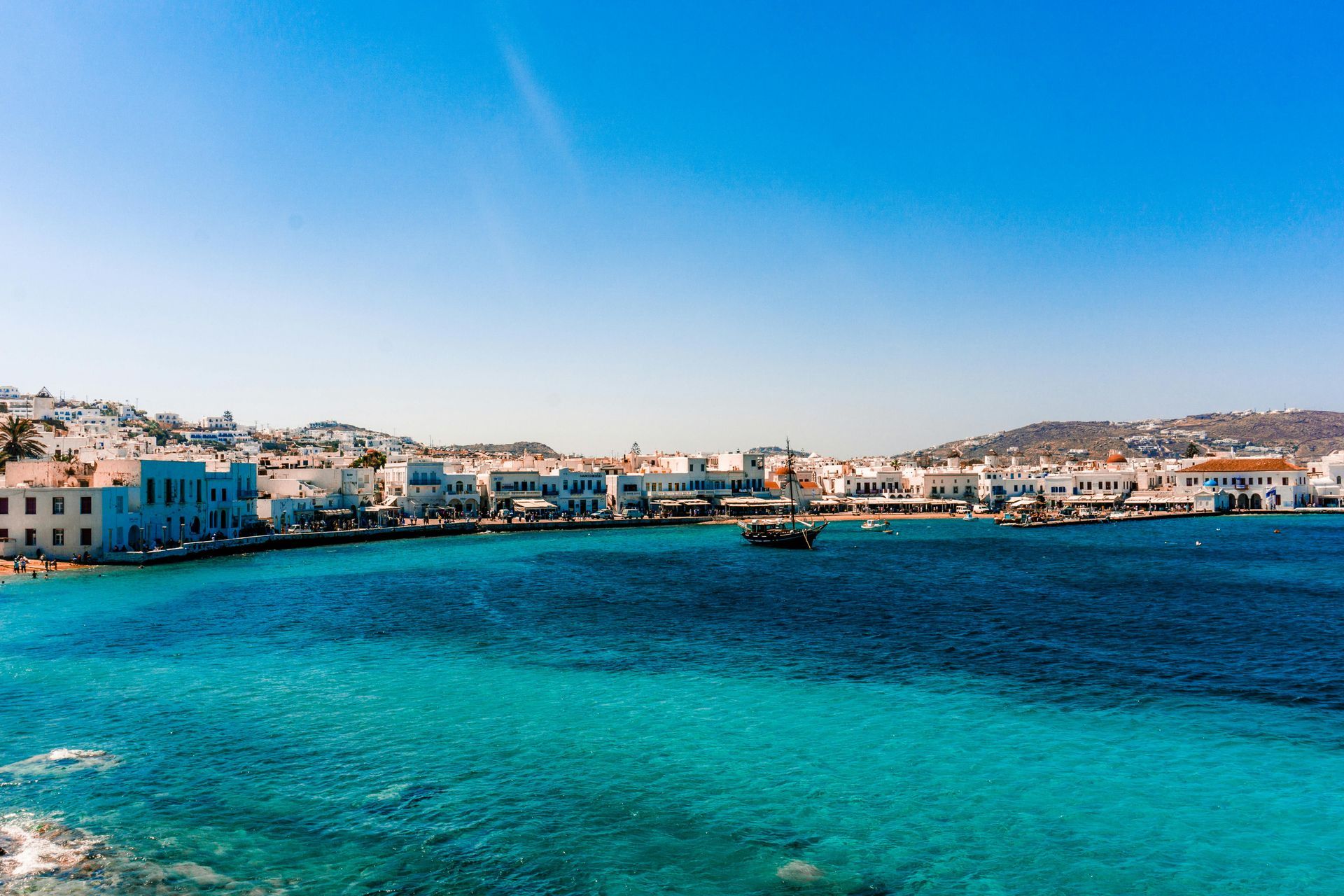 A boat is in the water near a city on a sunny day.