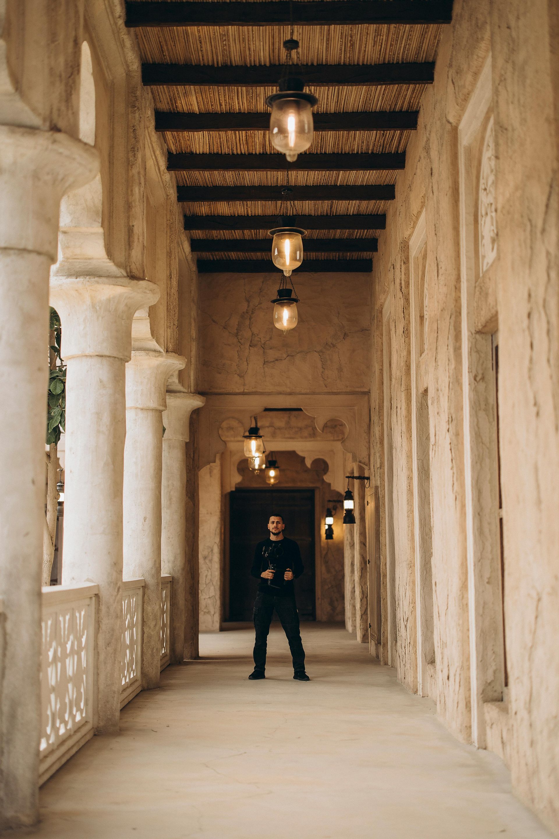 A man is standing in a long hallway between two buildings.