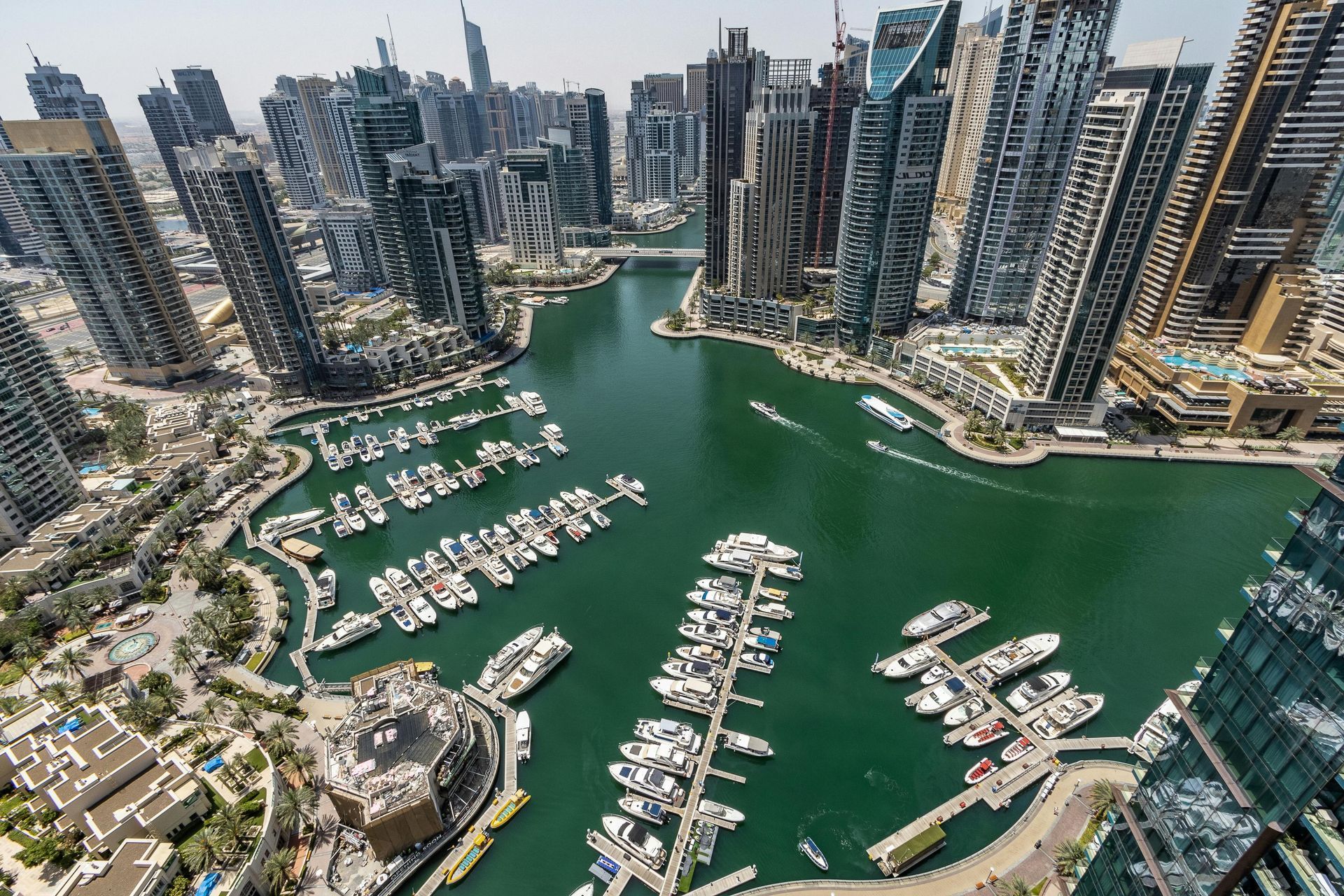 An aerial view of a city with boats docked in a harbor surrounded by tall buildings.