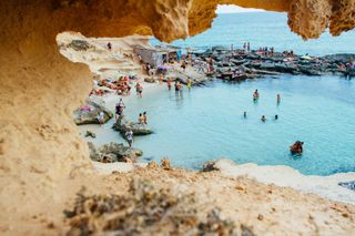 A group of people are swimming in the ocean on a beach.
