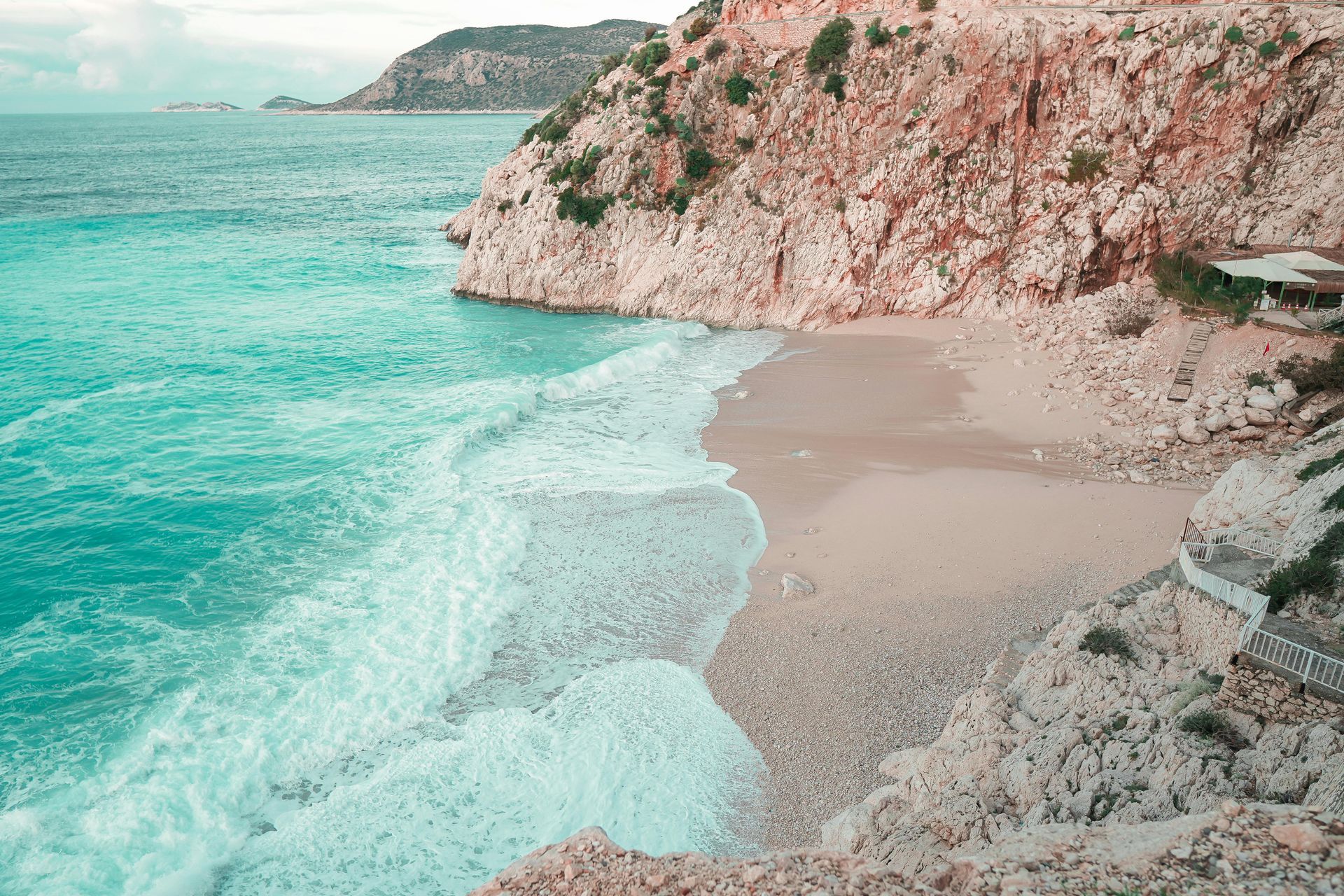 An aerial view of a beach with waves crashing on the shore.