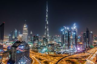 A city skyline at night with a very tall building in the middle.