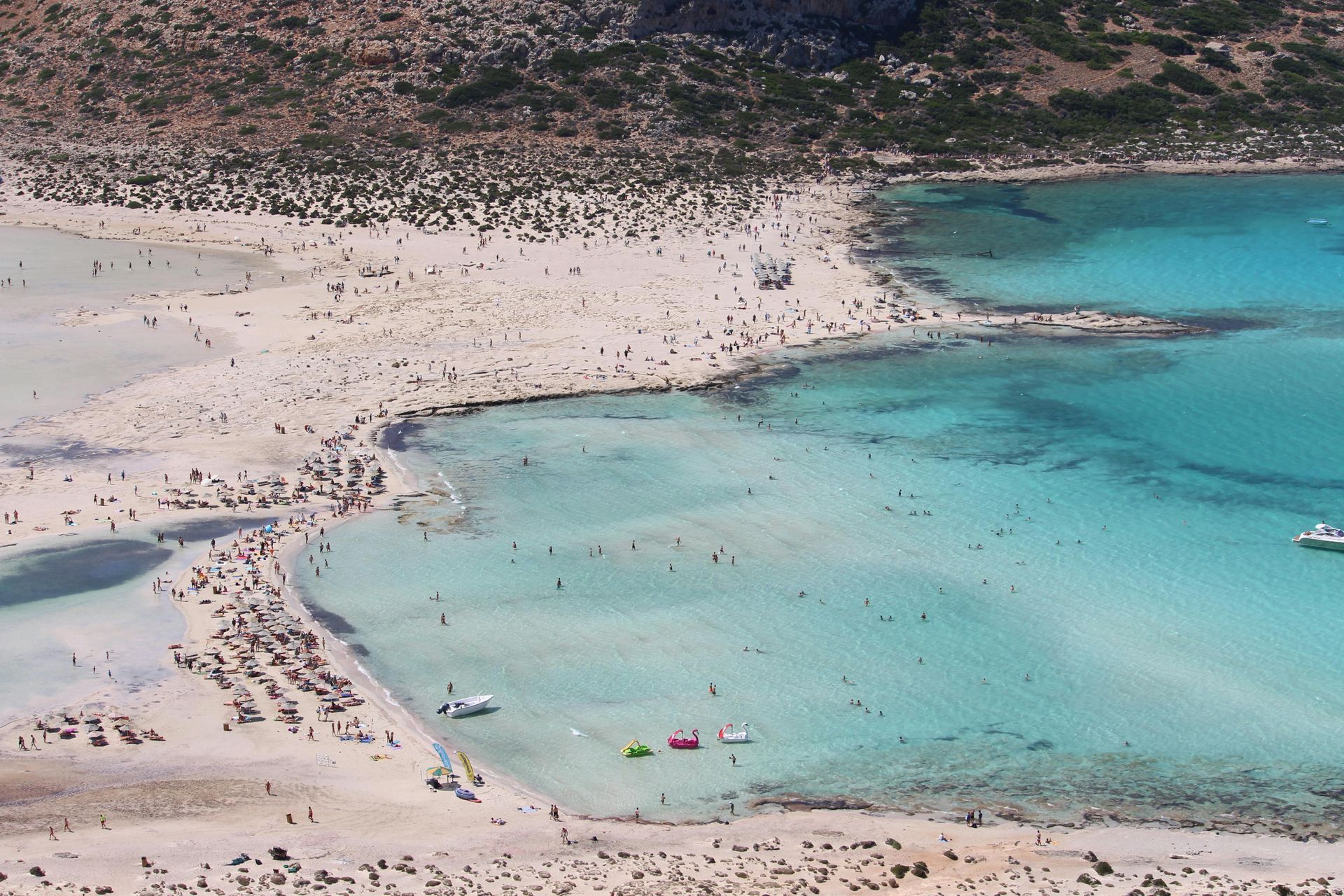 An aerial view of a beach with boats in the water
