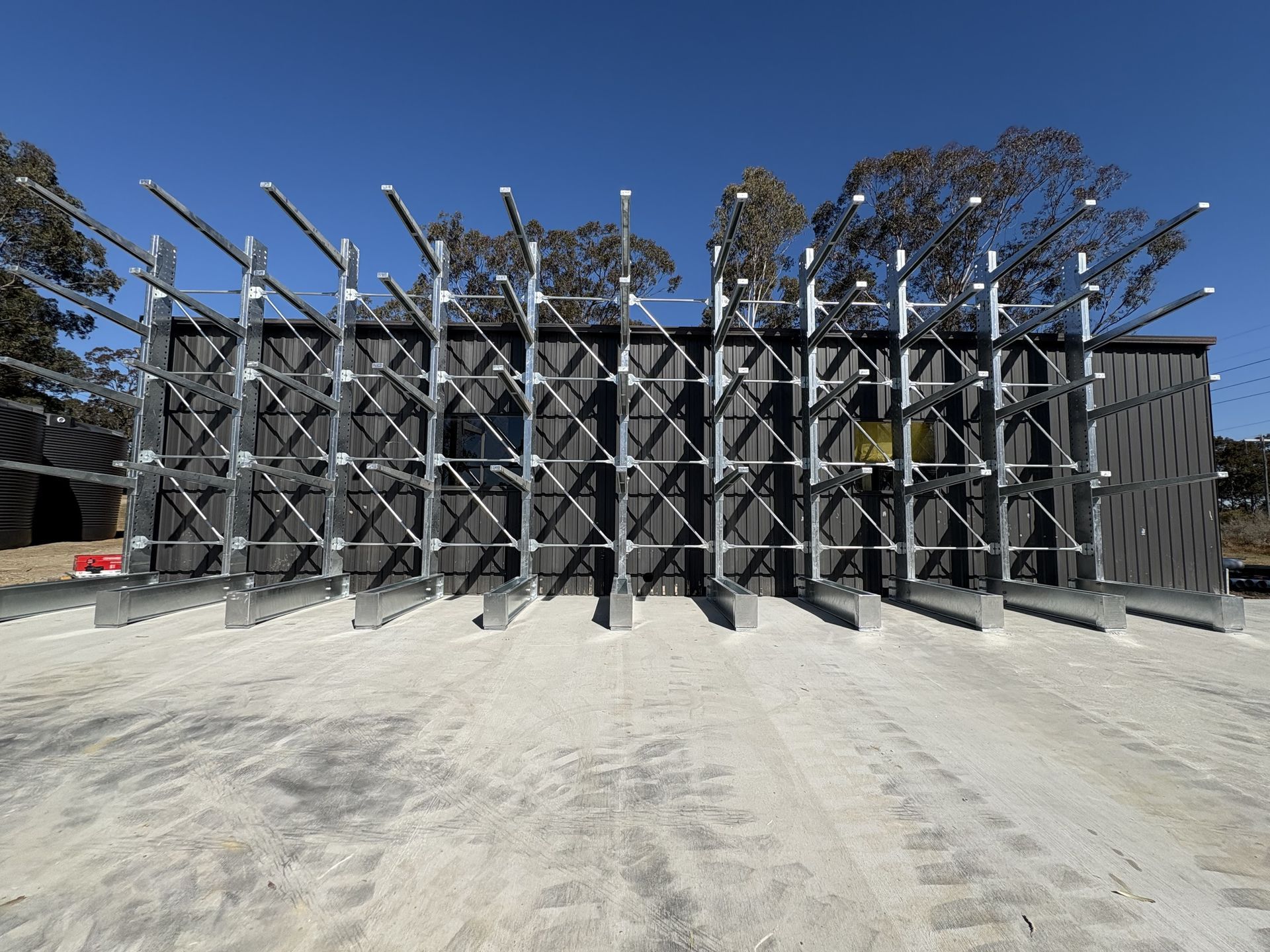 Large metal framework with angled pipes in a dusty yard under a clear blue sky — Shop Fittings Office Furniture Materials Handling In Central Coast, NSW
