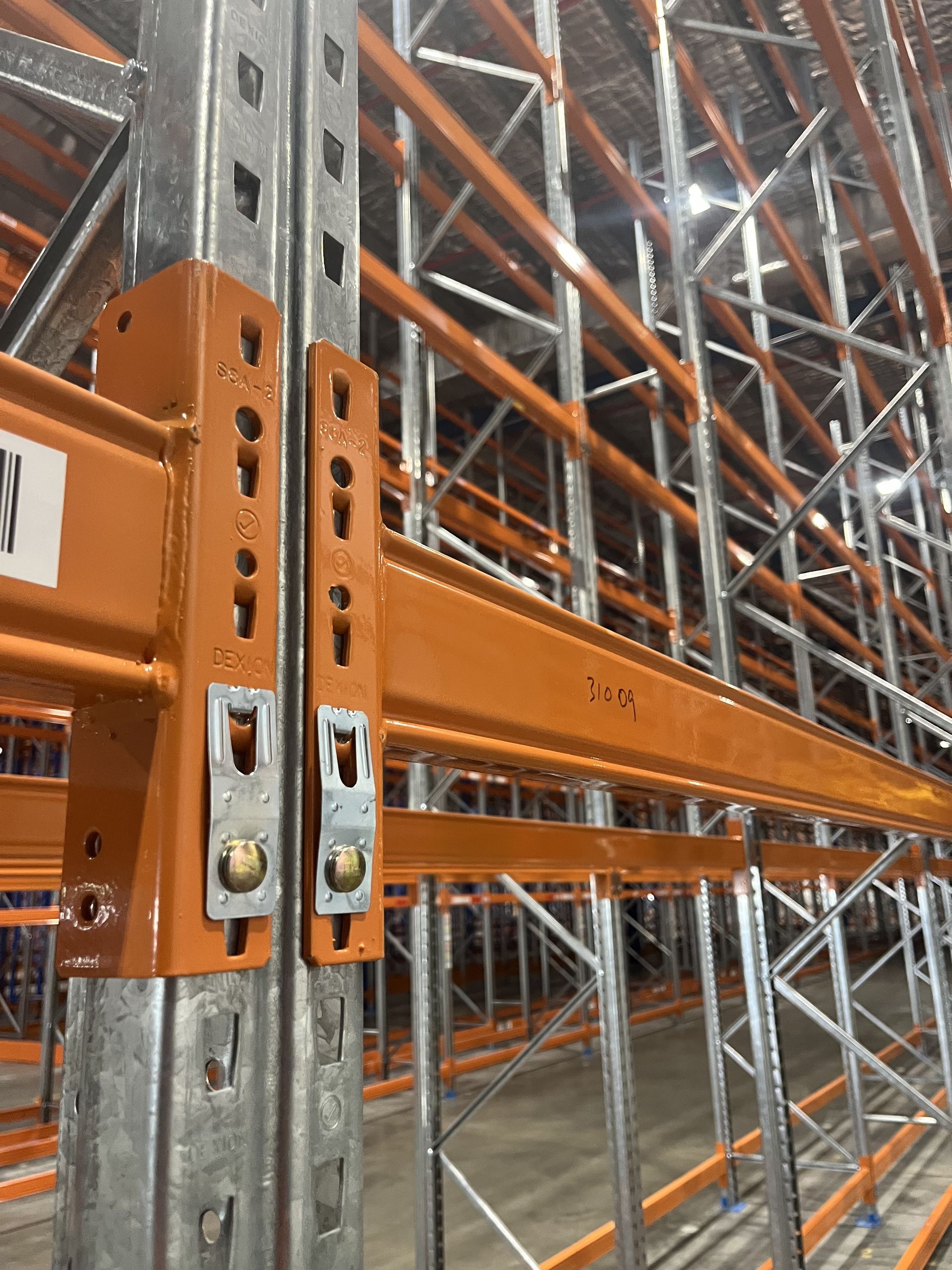 Orange and silver warehouse pallet rack with steel beams and cross-bracing in an industrial aisle