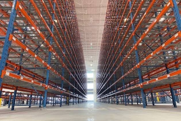 Empty warehouse aisle with tall orange-and-blue storage racks on both sides — Shop Fittings Office Furniture Materials Handling In Gosford, NSW
