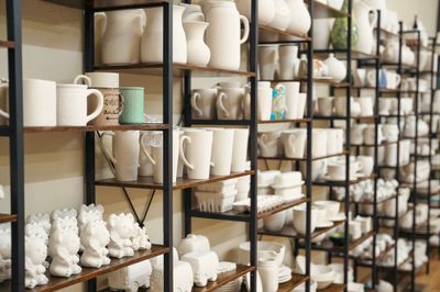 Shelves of white and cream ceramic mugs, teapots, and decor in a bright store display