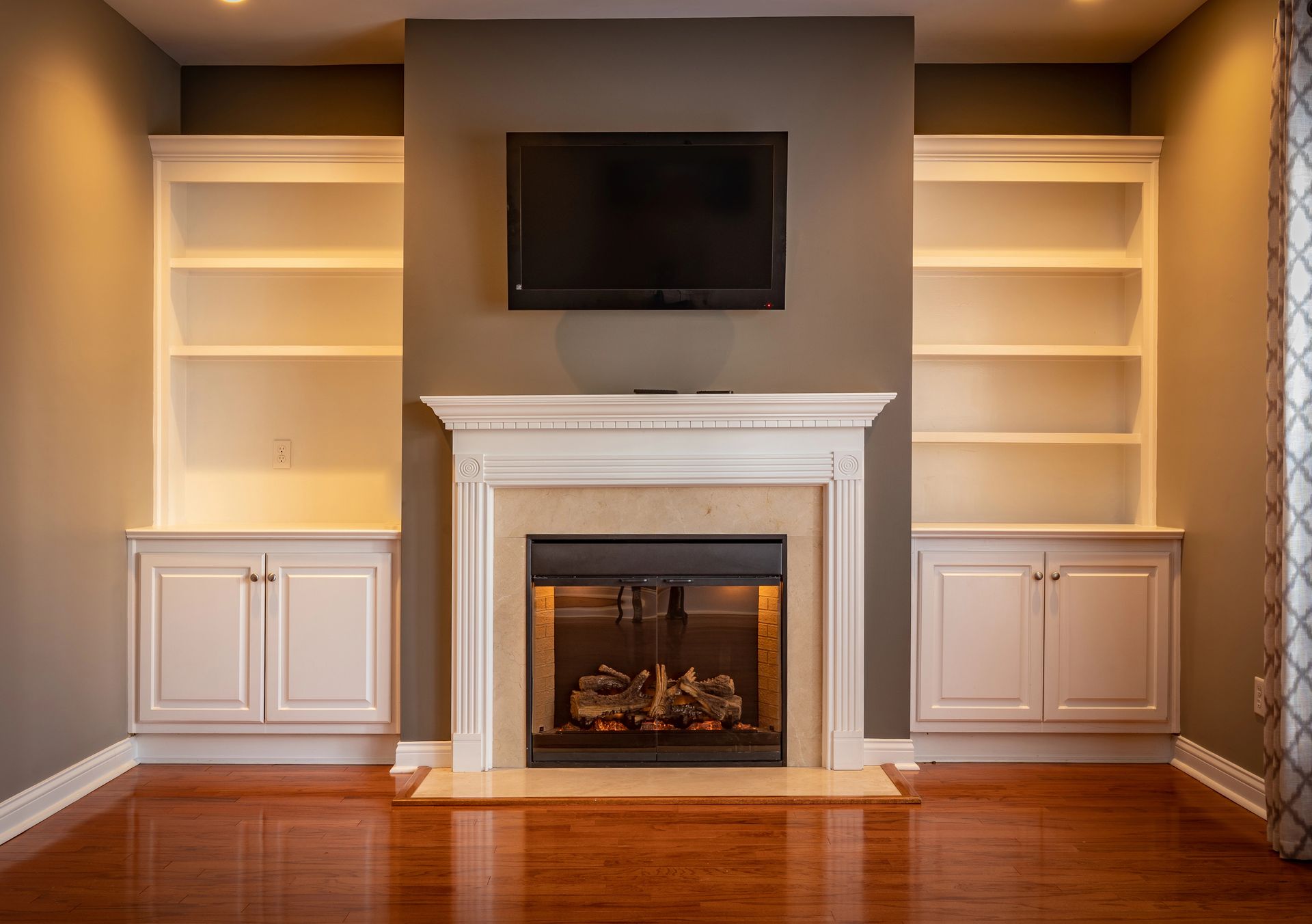 A living room with a fireplace , shelves , and a flat screen tv.