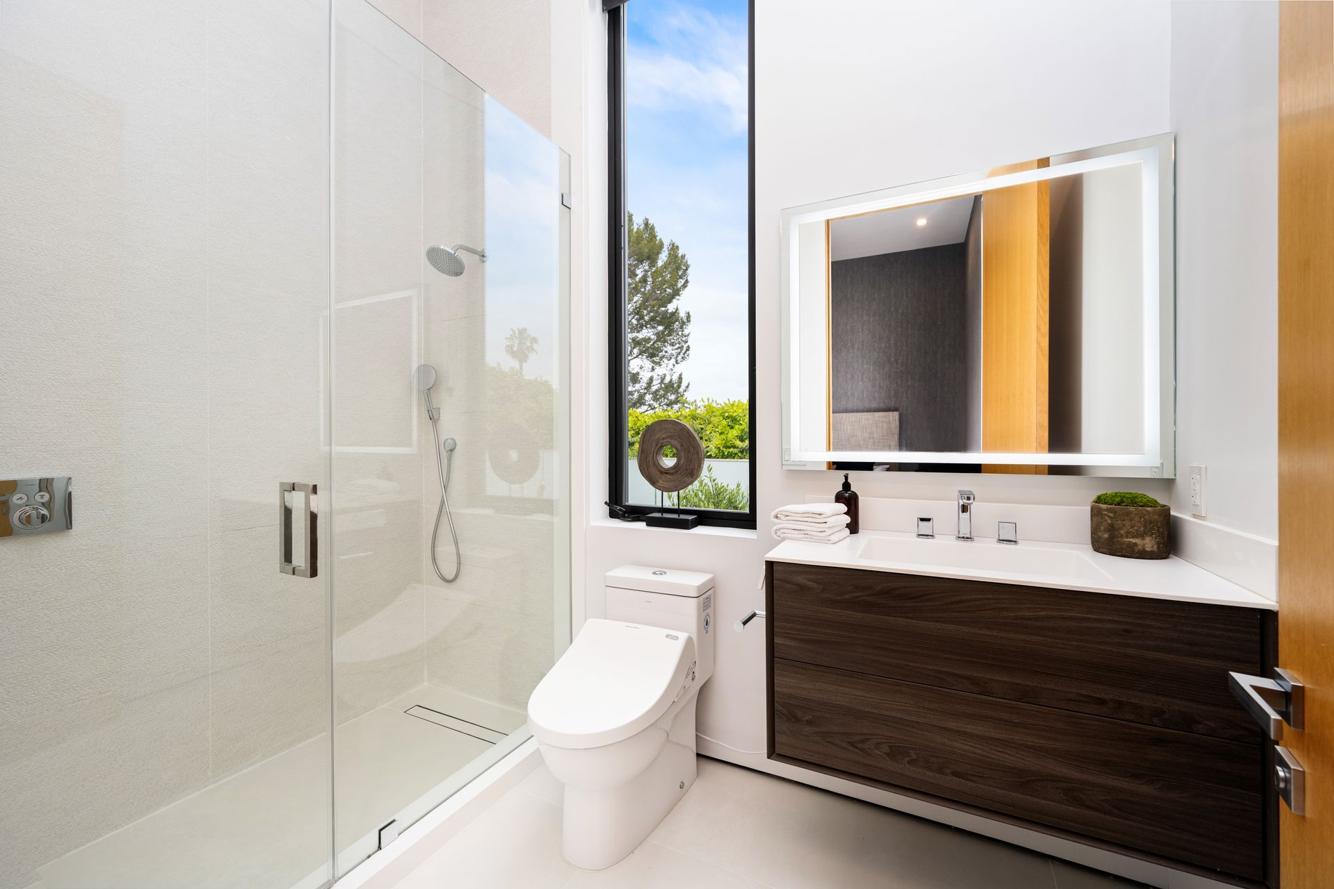 A bathroom with a toilet , sink , shower and mirror.