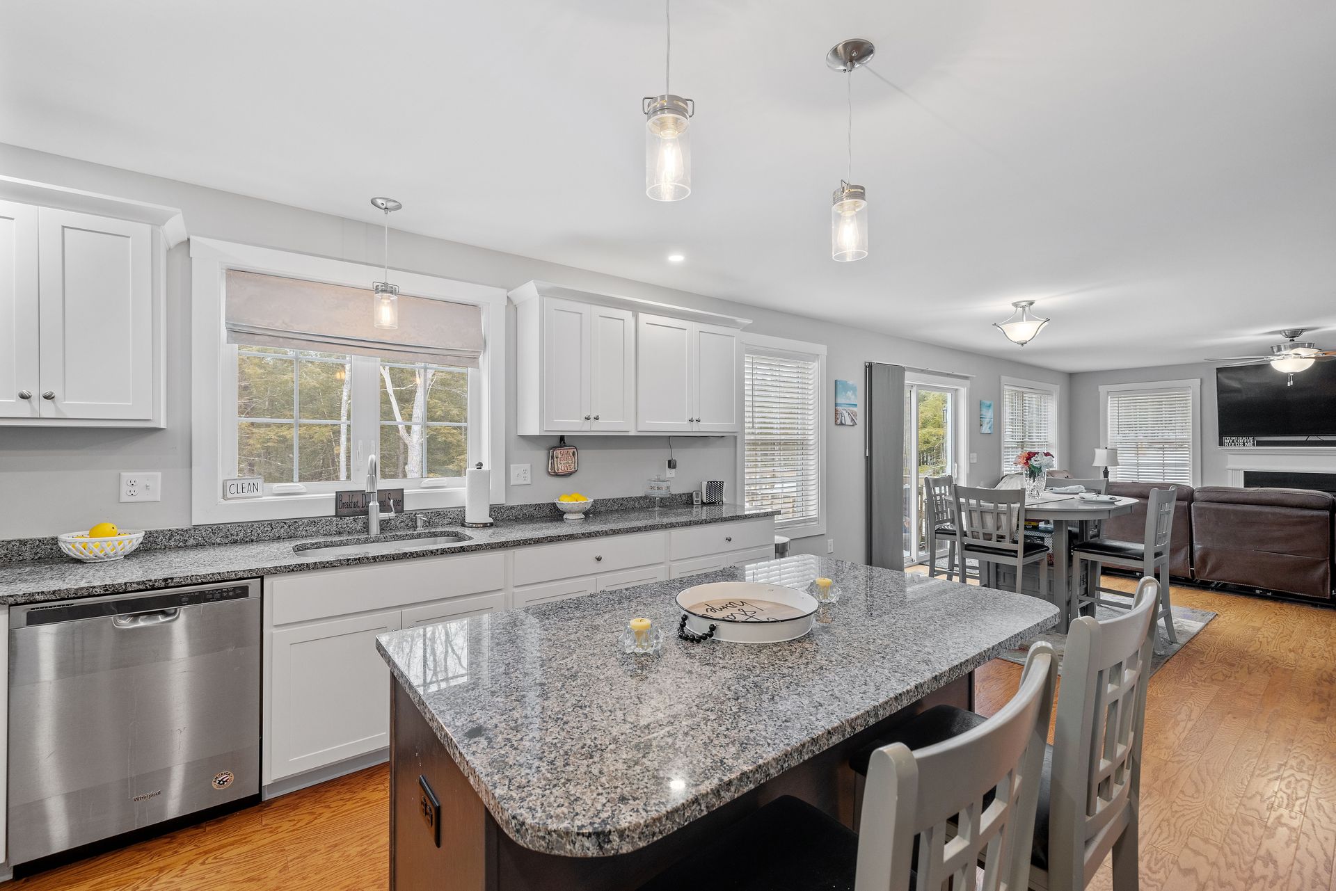 A kitchen with granite counter tops , stainless steel appliances , and white cabinets.