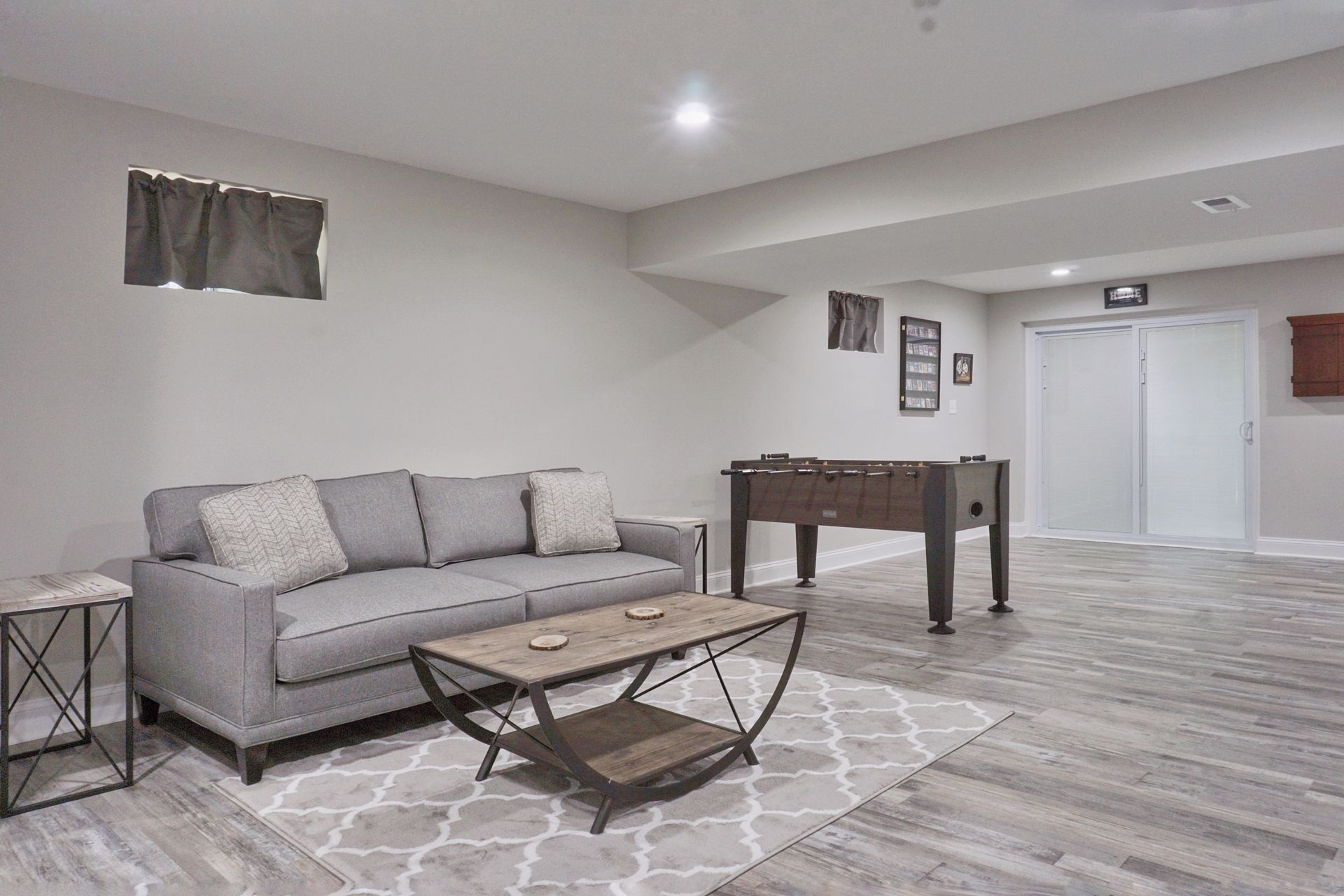 A living room with a couch , coffee table , and foosball table.