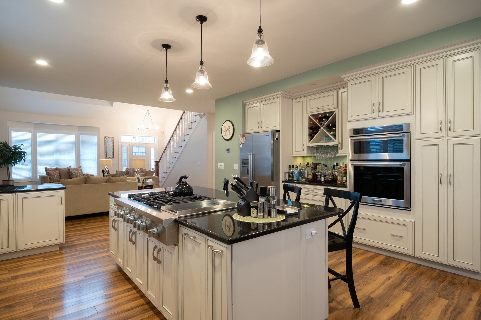 A kitchen with white cabinets , black counter tops , stainless steel appliances and a large island.